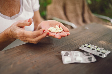 Senior old woman hands holding vitamins pills outdoors in garden. Healthcare aged people concept