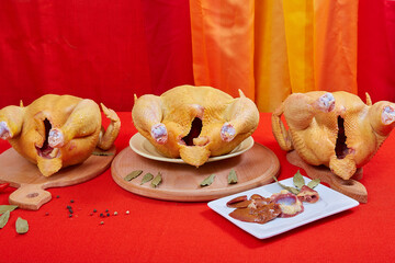 Three raw chicken on red background. © Malsveta