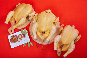 Three raw chicken on red background. © Malsveta
