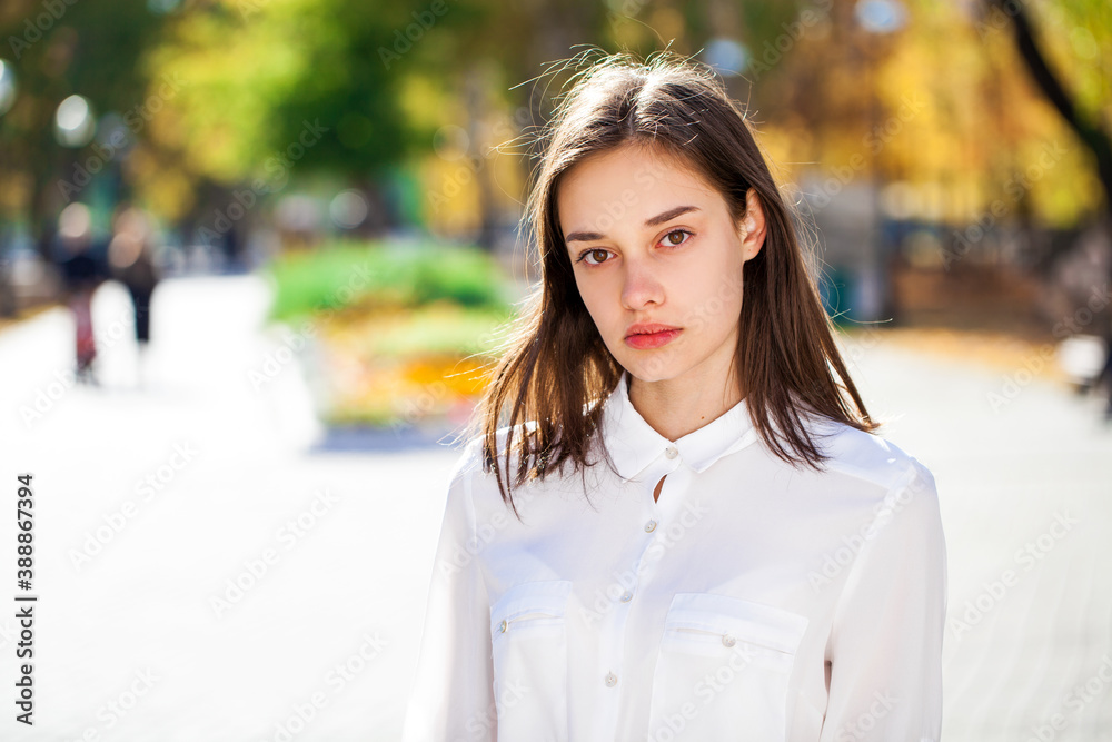 Wall mural Close up portrait of a young brunette girl in white shirt