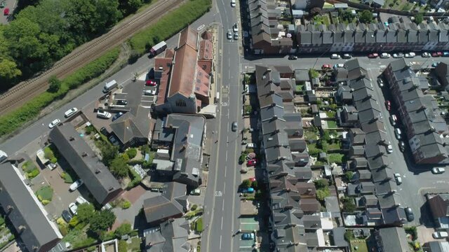Aerial of train line and residential streets in urban england on a sunny day, river and community facilities also visible