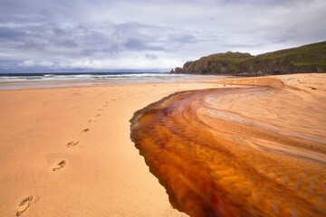 The red river runs down to Dalmore beach on the Isle of Lewis 