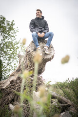 Young Man SItting On Top Of A Fallen Tree Up High