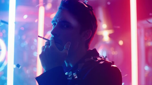 Thinking man blowing smoke at party in slow motion. Hot guy smoking in nightclub