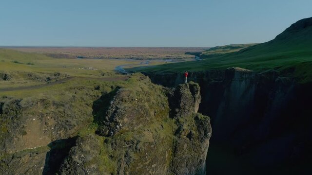 Epic cinematic drone shot of man stand on edge of cliff or rock in Iceland or Norway. Adventurer urban nomad, travel blogger shoot content on smartphone. Amazing adventures lifestyle