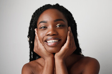 Close-up of young black attractive woman with beautiful smile, posing over white background. Skin...