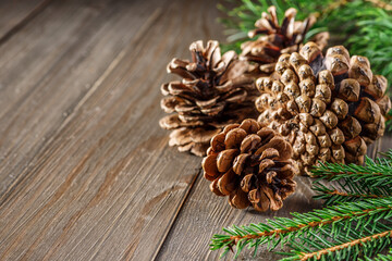 Pine cone and green branch on wooden table with snow, copy space for text.Christmas card. Pine cones on wooden background.
