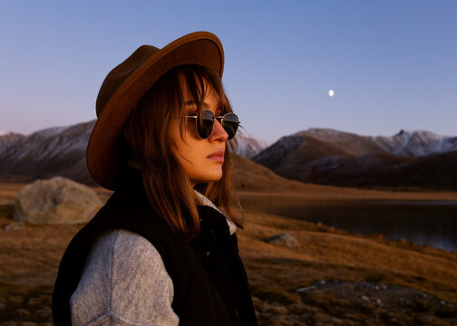 beautiful girl in sunglasses and a hat on a background of a beautiful mountain landscape.