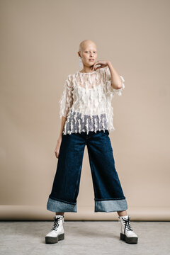 Bald female model in trendy outfit looking at camera