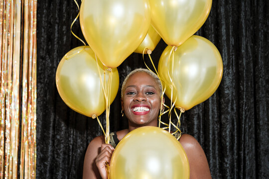 Happy woman with yellow balloons looking at camera