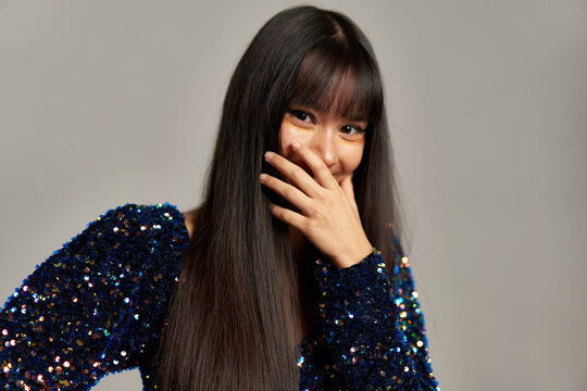 Serious long haired woman in shiny dress looking at camera