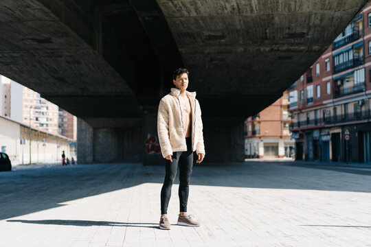 Trendy guy standing under bridge