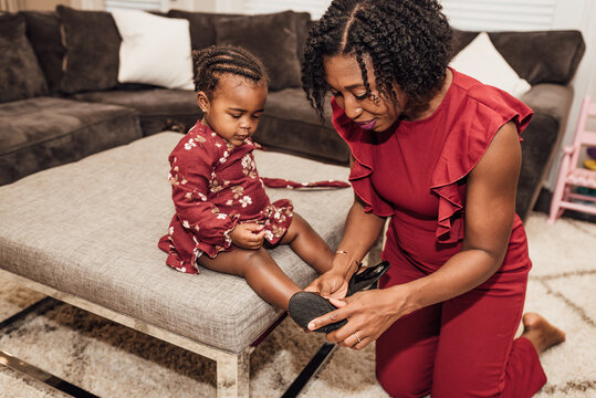 Mom putting on daughters shoe