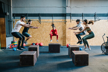 Group of athletes jumping on cubes during training