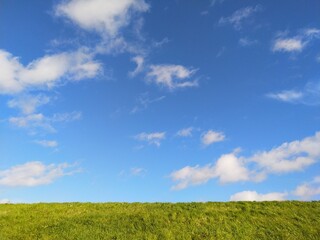 blue sky with white clouds and green grass background