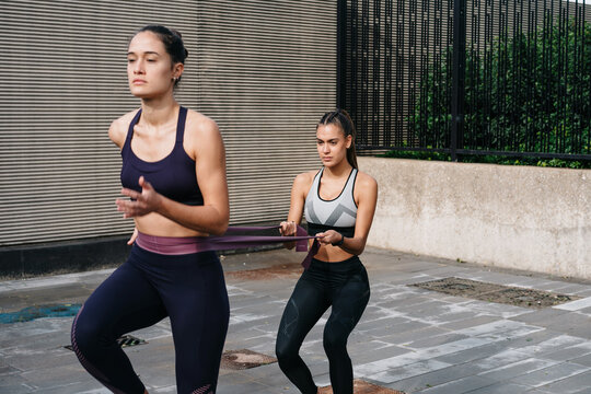 Sportswomen in active clothing doing resistance exercises togeth