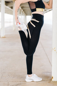 Young sportswoman strechingl on street