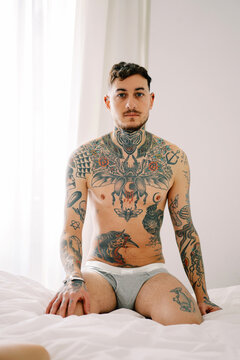 Tattooed man sitting in bed