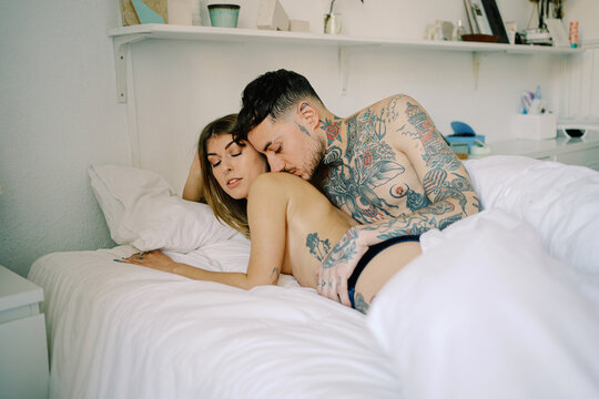 Tattooed man embracing semi naked girlfriend