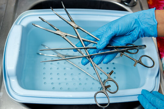 A medical worker rinses surgical instruments in a tray of water. Disinfection of medical equipment