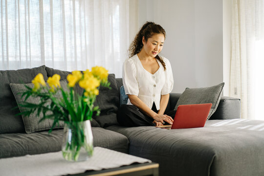 Asian Woman Using Laptop On Sofa