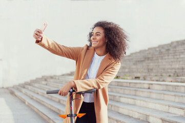 woman takes a selfie photo with the mobile phone has an electric scooter