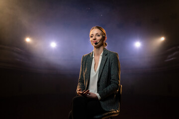 Expert perform on the stage address to modern crowd audience sitting and listening in large hall. Female entrepreneur communicating with a listener at workshop convention for young businesspersons