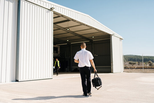 Male aviator with bag walking on aerodrome
