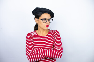 Young beautiful brunette woman wearing french beret and glasses over white background thinking looking tired and bored with crossed arms