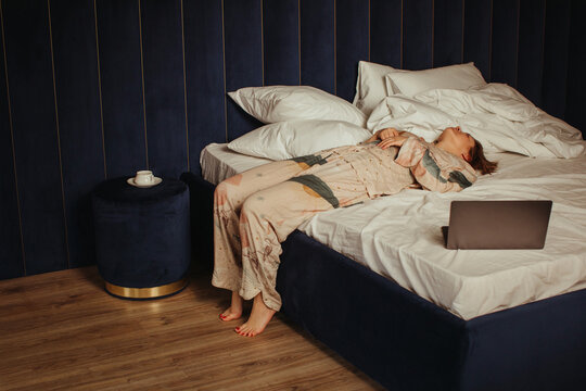 Tired woman laying on bed near laptop