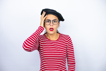 Young beautiful brunette woman wearing french beret and glasses over white background putting one...