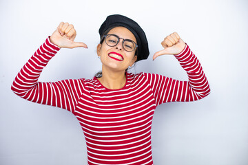 Young beautiful brunette woman wearing french beret and glasses over white background looking...