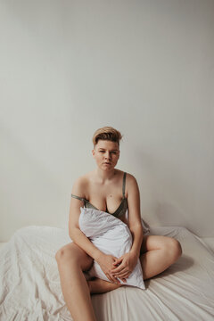 Real body type young woman sitting on bed