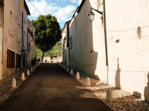 A calm street with a public bench and a tree in the rural town of Beaune, Burgundy, France.
