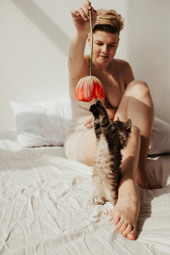 Sensual woman playing with kitten on bed