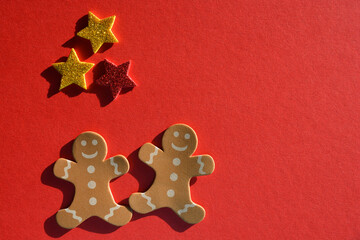 Gingerbread men and glitter stars isolated on red background with copy space