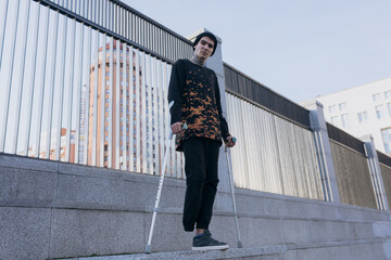 invalid guy stands on crutches on the street