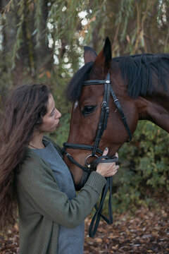 photo of a dark-skinned girl with long curly hair with her brown horse in nature