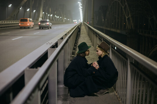 a couple of gays in a coat crouched on the pedestrian part of the bridge and joined hands