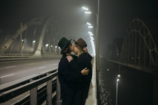 guy kisses his boyfriend on the bridge at night
