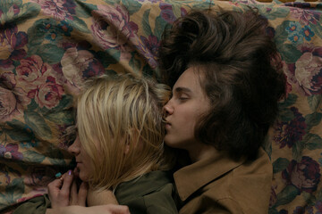 Portrait of two sleeping gays on a bed with tousled hair.