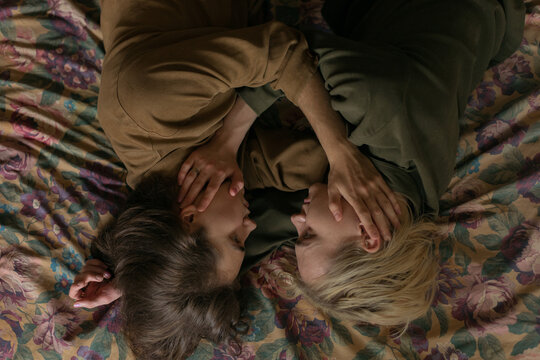 two gays lie on the bed in stroking each other's faces