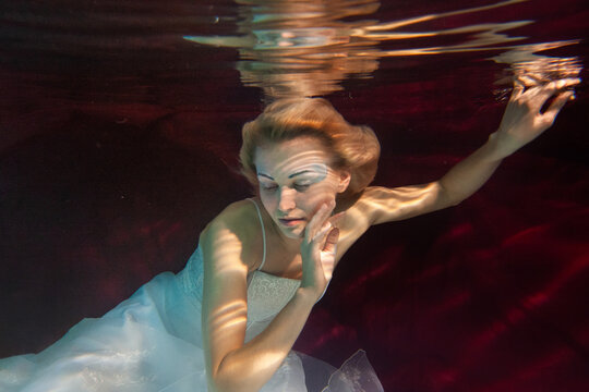 artistic woman wearing wedding dress underwater