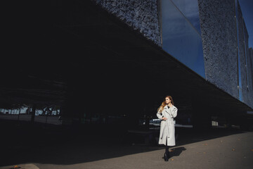 Pretty woman with curly hair posing near modern city build.