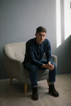 the guy is sitting on a high chair and looking seriously at the camera