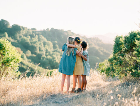 Childhood summer - Three young girls hug carefree in the sunset