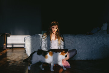 Teenager studying near bed with cat.
