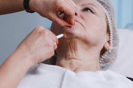 Anonymous person marking line on facial skin.