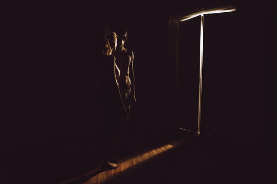 Silhouette of girl and boy standing near luminous door