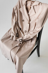 stylish trench coat on chair and white background